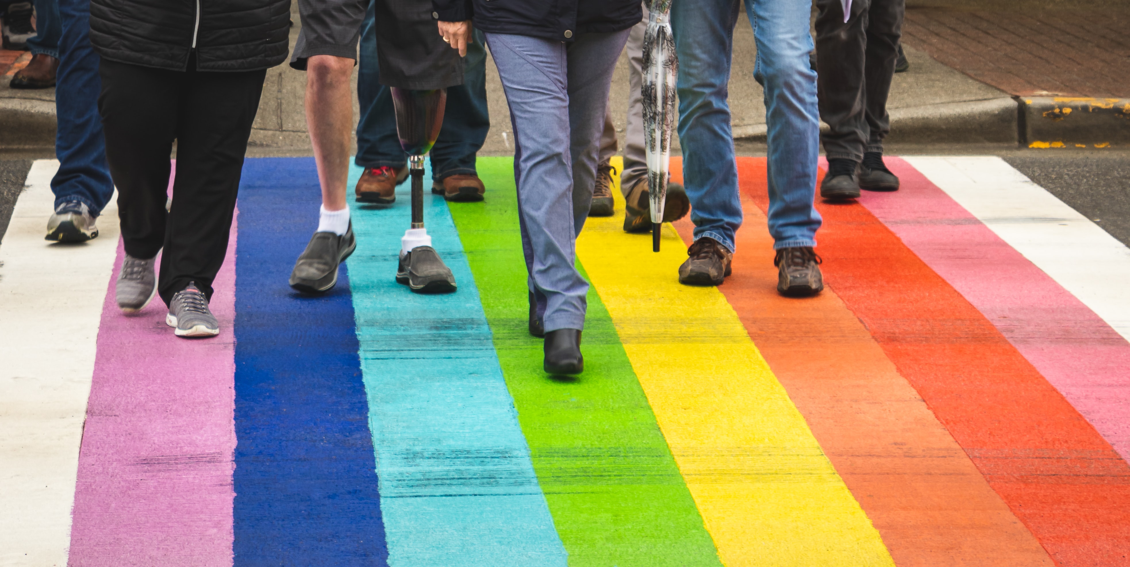 a group of diverse people walking on a multi-colored path